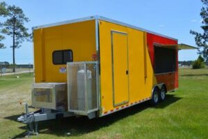 A yellow and red trailer parked in the grass.