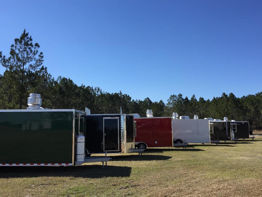 A row of trailers parked in the grass.